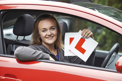 Girl sitting in a car smiling as she has just passed her driving test
